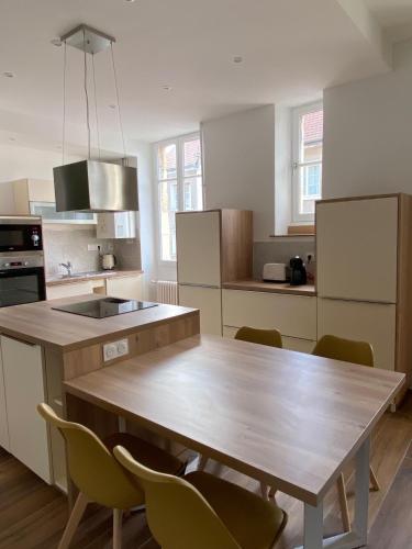 une cuisine avec une table en bois et quelques chaises dans l'établissement Le VH - Appartement 3 chambres, à Dijon