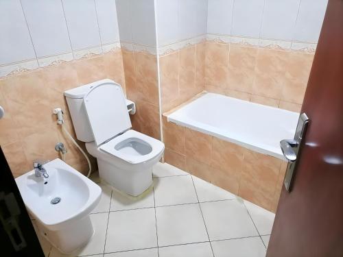 a bathroom with a toilet and a tub and a sink at MBZ - Cosy Separate Room in Unique Flat in Abu Dhabi