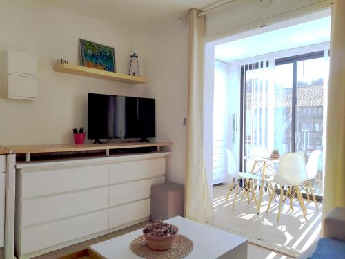 ein Wohnzimmer mit einem TV und einer Glasschiebetür in der Unterkunft T2 Proche Capelan -parking privé gratuit - wifi in Bandol