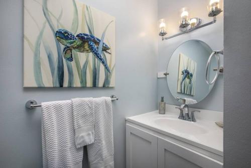 a bathroom with a sink and a mirror and towels at Gorgeous One Bedroom golf course front in Kahuku