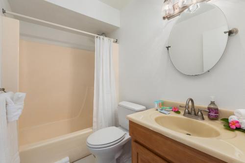 een badkamer met een wastafel, een toilet en een spiegel bij Beautiful Golf Course front near the beach in Kahuku