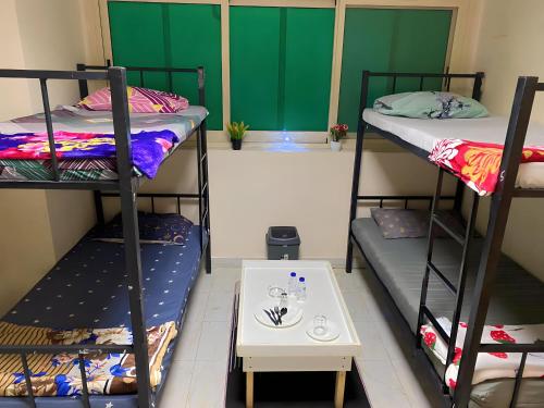 a room with three bunk beds and a table at MBZ - Nice Bed Space "MEN" in Abu Dhabi