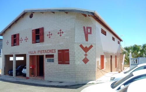 un pequeño edificio de ladrillo blanco con puertas y ventanas rojas en Villa Pistaches, en Grand-Bourg