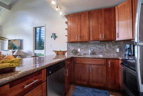 a kitchen with wooden cabinets and a black dishwasher at Fantastic Location on the golf course near the beach in Kahuku