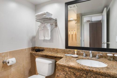 a bathroom with a sink and a toilet and a mirror at Incredible Location FREE parking in Waikiki in Honolulu