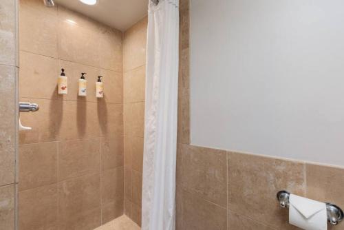 a bathroom with a shower with three shampoo bottles at Incredible Location FREE parking in Waikiki in Honolulu