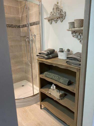 a bathroom with a shower and a wooden shelf with towels at Les Gîtes de La Petite Campagne in Mane