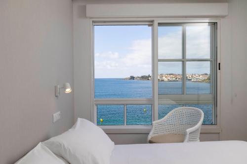 1 dormitorio con ventana y vistas al océano en Apartamentos Rotilio en Sanxenxo