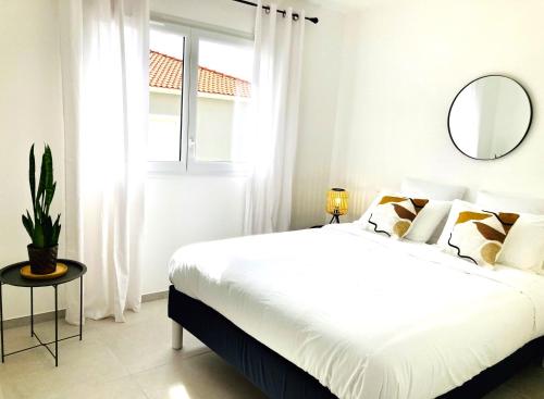 une chambre blanche avec un grand lit et un miroir dans l'établissement Sognu di Serena - Superbe appartement avec parking gratuit sur place, à Porto-Vecchio