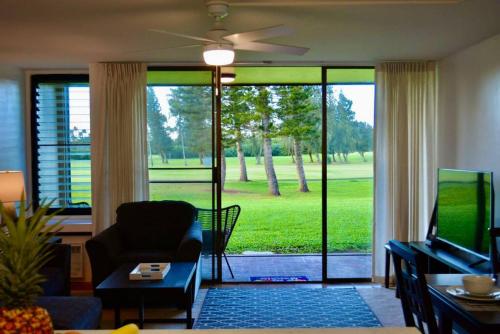 a living room with a couch and a tv and sliding glass doors at Beach Glam at Turtle Bay on the golf course in Kahuku