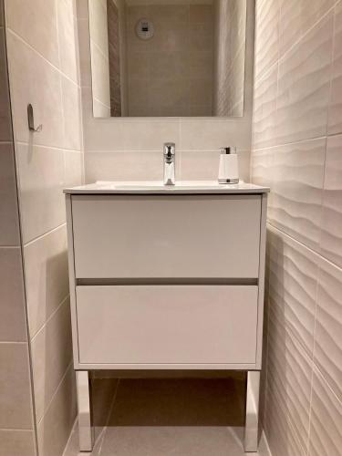 une salle de bain avec un lavabo blanc et un miroir dans l'établissement Sognu di Serena - Superbe appartement avec parking gratuit sur place, à Porto-Vecchio