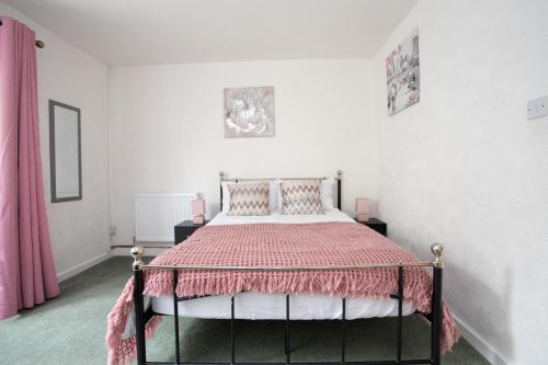 a bedroom with a bed with a pink comforter at Hurley House in Cheadle Hulme