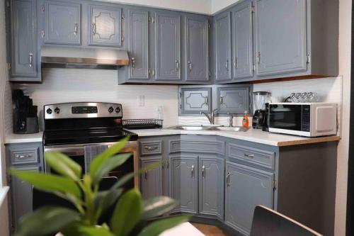 cocina con armarios azules, fogones y microondas en Cozy 2-Bedroom Rental Unit, en Eagle Pass