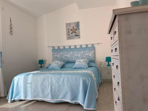 a bedroom with a blue bed and a dresser at Case del Mar in Santa Teresa Gallura