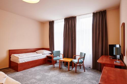a hotel room with a bed and chairs and a television at Hotel Terasa in Vimperk