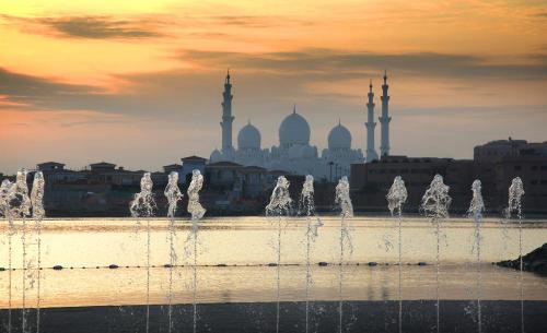 a fountain in front of a city with mosques at Fairmont Bab Al Bahr in Abu Dhabi
