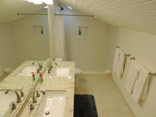 a white bathroom with two sinks and a toilet at Spacious Townhouse by the beach in Kahuku