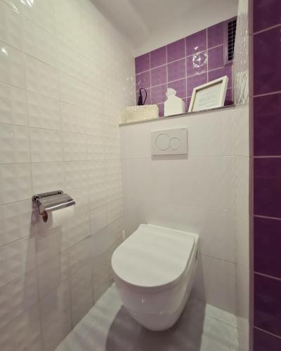a white toilet in a bathroom with purple tiles at Kieler Eiderparadies in Flintbek