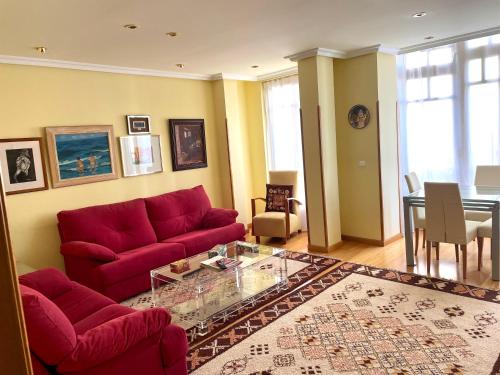a living room with a red couch and a table at APARTAMENTO CARMEN in Gijón
