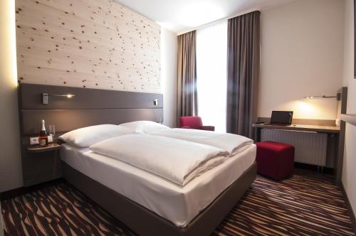a hotel room with a large bed and a desk at Amaro Hotel in Bergkirchen