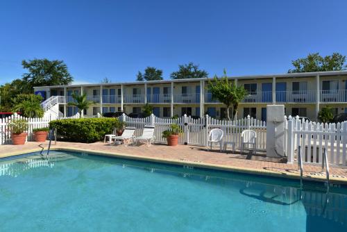 a building with a white fence and a swimming pool at Americas Best Value Inn Bradenton-Sarasota in Bradenton