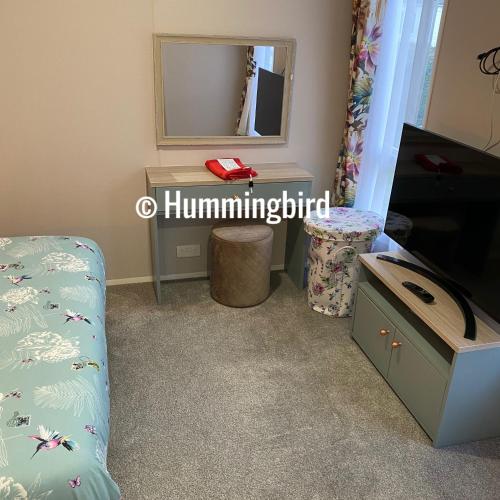 a room with a tv and a table and a mirror at Hummingbird Retreat in Blackpool