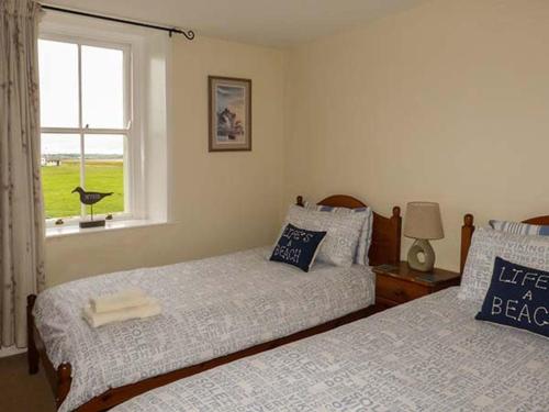 two beds sitting in a bedroom with a window at Gulls Hatch in Maryport
