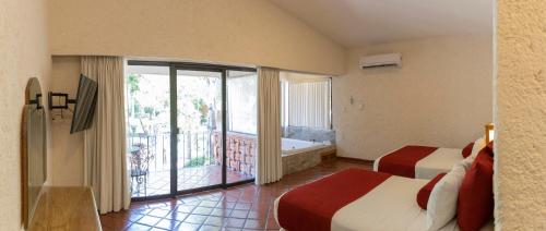 a bedroom with two beds and a balcony with a tub at Hosteria Las Quintas Hotel Restaurante Bar in Cuernavaca
