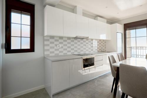 a kitchen with white cabinets and a table with chairs at Sunbreeze Delux Vilas in Budva