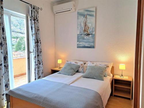 una camera da letto con un letto con due lampade e una finestra di Rooms Irena Gregov a Mošćenička Draga