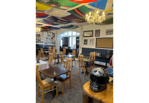 a dining room with tables and chairs and a helmet on a table at OYO Lord Kitcheners Guest House in Lowestoft