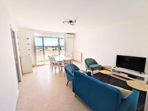 uma sala de estar com um sofá azul e uma televisão em Grand Appartement Ensoleillé avec Parking em Nîmes