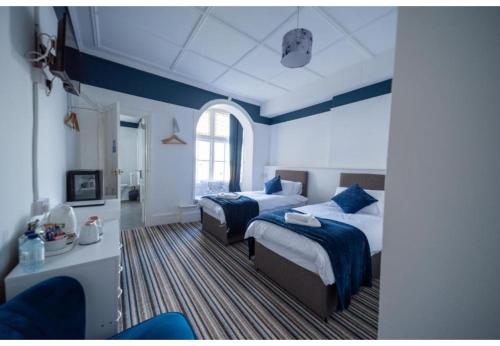 een slaapkamer met 2 bedden en een blauwe muur bij OYO Lord Kitcheners Guest House in Lowestoft