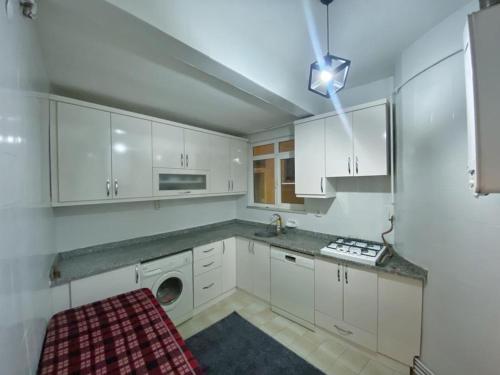 cocina con armarios blancos y techo con luz en Şişli House, en Estambul