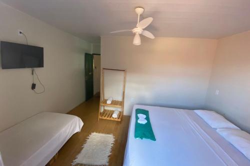 a bedroom with two beds and a ceiling fan at Pousada do beco in Caravelas