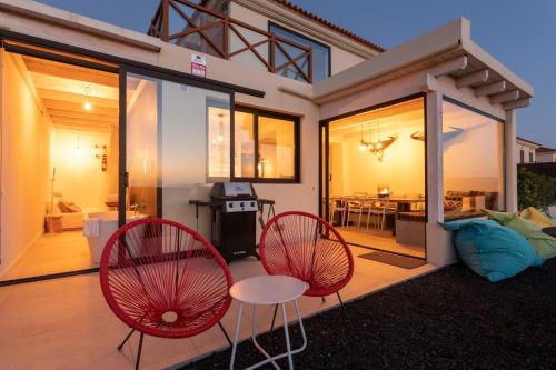 a house with two red chairs and a patio at Villa Calderón Hondo. Top design , views and pool Lajares-Corralejo in Corralejo