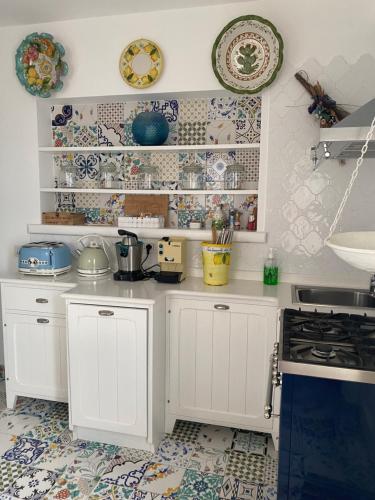 a kitchen with white cabinets and plates on the wall at La Baia di Napoli in Capri