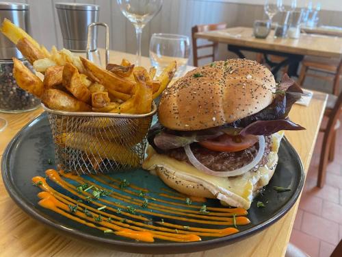 a plate with a hamburger and french fries on a table at Chambre indépendante Au Relais Normand in Cormeilles