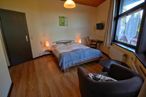 una camera con letto, divano e sedia di Dein Hotel Suite Wellness a Hahnenklee-Bockswiese