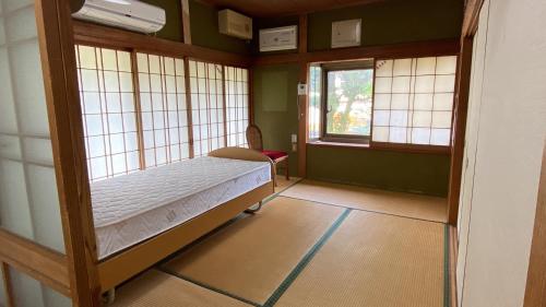 a bedroom with a bed in a room with windows at 旅する人生ハウス鹿屋 in Kanoya