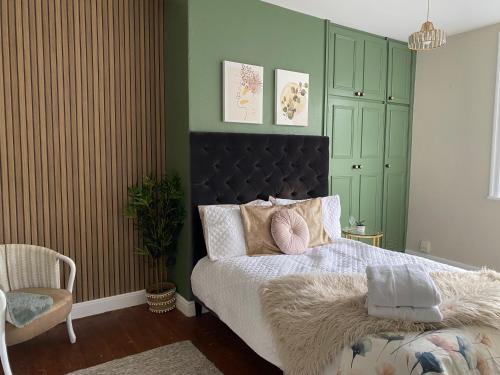 a bedroom with a bed with a black headboard and a chair at Cobble Cottage in Lindley