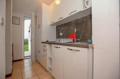 une cuisine avec des placards blancs et un comptoir dans l'établissement Apartment Camelia, à Poreč