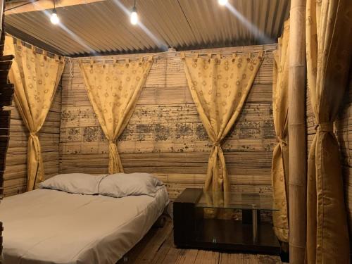 1 dormitorio con cama, mesa y cortinas en Glamping la veranera en San Vicente