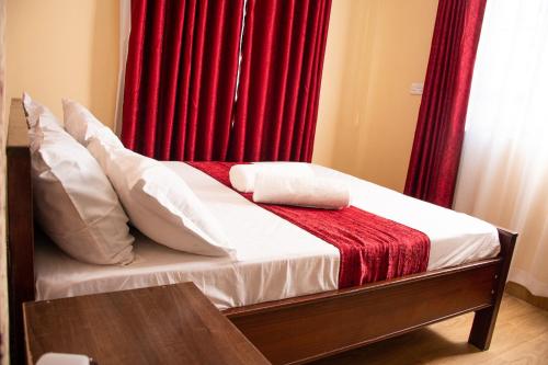 a bedroom with a bed with a red curtain at Pearl suites in Bungoma