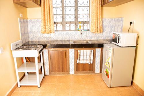 una pequeña cocina con nevera y microondas en Pearl suites, en Bungoma