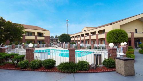 a pool in front of a building with a white fence at Magnuson Hotel Virginia Beach in Virginia Beach