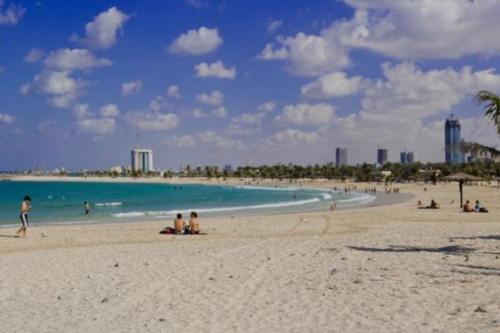 a group of people on a beach with the ocean at Beach view, Cozy 2BR apartment in Sharjah