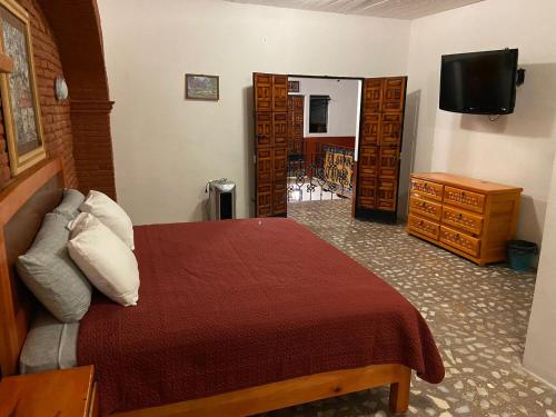 a bedroom with a bed with a red blanket and a television at EL GRAN TORIL in Taxco de Alarcón