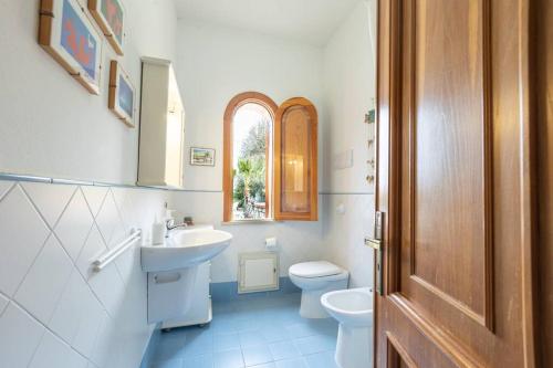 Un baño con lavabo, inodoro y ventana. en 3-Casa sul mare con piscina vicino Cefalù, en Campofelice di Roccella