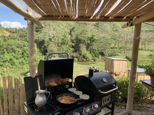 a grill with food on it under a pergola at Glamping la veranera in San Vicente